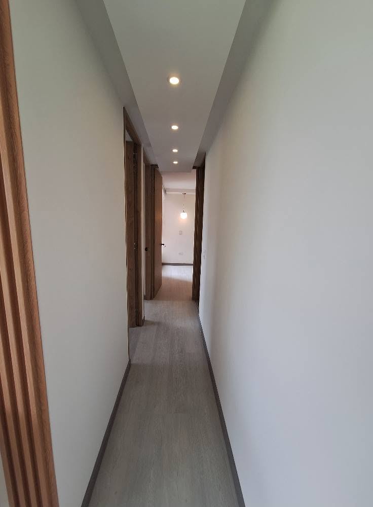 Pasillo con puertas en madera, guardaescobas e iluminación empotrada